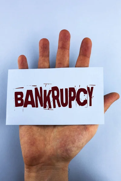 Word writing text Bankrupcy. Business concept for Company under financial crisis goes bankrupt with declining sales written on Sticky Note Paper placed on Hand on the plain background.
