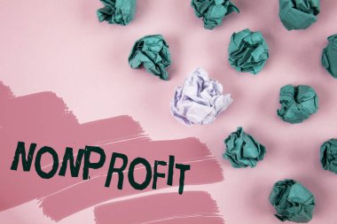El yazısı metin Nonprofit. Pembe boyalı arka plan buruşuk kağıt topları yanındaki yazılı executor için gelirleri elde edebilirim faaliyetleri anlam kavramı.