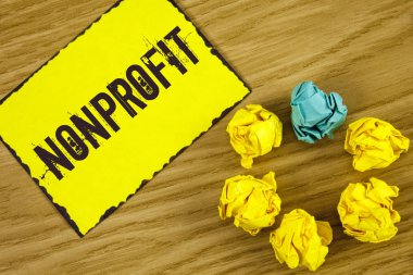 El yazısı metin Nonprofit. Ahşap arka plan buruşuk kağıt topları yanında yapışkan not kağıdına yazılı executor için gelirleri elde edebilirim faaliyetleri anlam kavramı.