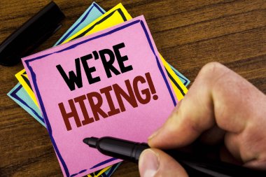 Word metin çoğu işe motivasyonel dediğimiz yazma. İş kavramı işgücü istedim yeni çalışanları tarafından adam pembe yapışkan not kağıt holding marker ahşap arka plan üzerinde yazılı işe alım için 