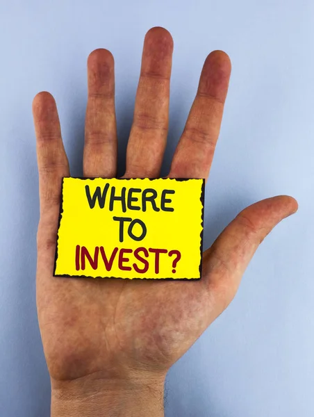 Znak tekstowy pokazuje gdzie inwestować pytanie. Koncepcyjne Zdjęcie prawo miejsce Stock udział wydać oszczędności w pisemnej na żółtą karteczkę umieszczone na dłoni na tle zwykłego. — Zdjęcie stockowe