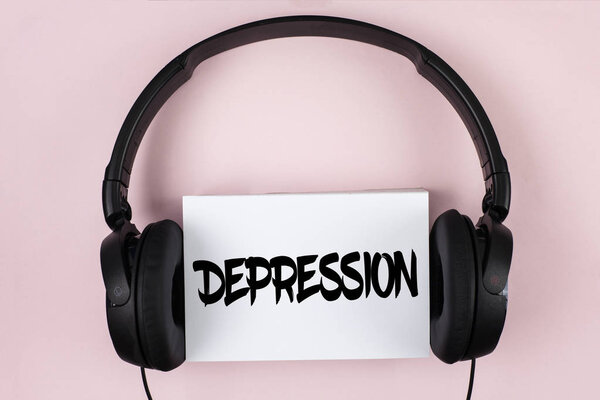 Handwriting text Depression. Concept meaning Work stress with sleepless nights having anxiety disorder written on White Sticky Note paper on plain Pink background Headphone next to it.
