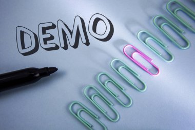 El yazısı metin Demo. Gösteri ürünleri yazılım şirketleri tarafından her yıl düz mavi arka plan üzerinde ataç ve damgalı yanında yazılı görüntülenir anlam kavramı.