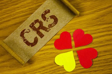 CRS. kavramsal gösterilen metin işaret yanında ahşap arka plan kağıt kalpleri üzerinde katlanmış karton kağıt parçası üzerinde yazılı vergi finansal bilgi paylaşımı için ortak raporlama standart fotoğraf