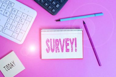 Survey 'i gösteren bir not yazıyorum. Önceden tanımlanmış bir gruptan veri toplamak için kullanılan iş fotoğrafı görüntüleme yöntemi. Tahta masaya yerleştirilmiş bilgisayar malzemeleri ve yazma ekipmanları..