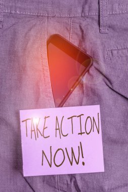 Kelime yazma metni Şimdi Harekete Geç. Resmi ya da uyumlu bir iş yapma kavramı, resmi iş pantolonu içindeki akıllı telefon aygıtı ile nota kağıdının yanındaki ön cebe ulaşmayı amaçlıyor.