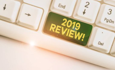 Kavramsal el yazısı 2019 İnceleme gösteren. Geçen yıl ki olayları hatırlayarak çekilen iş fotoğrafı ana eylemler veya iyi beyaz arka plan üzerinde not kağıdı ile Beyaz pc klavye gösterir.