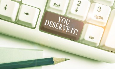 You Deserve It. Kavramsal fotoğraf nitelikleri veya eylemleri beyaz arka plan tuş kopyalama alanı üzerinde boş not kağıdı ile Beyaz pc klavye nedeniyle olmalıdır gösteren metin işareti.