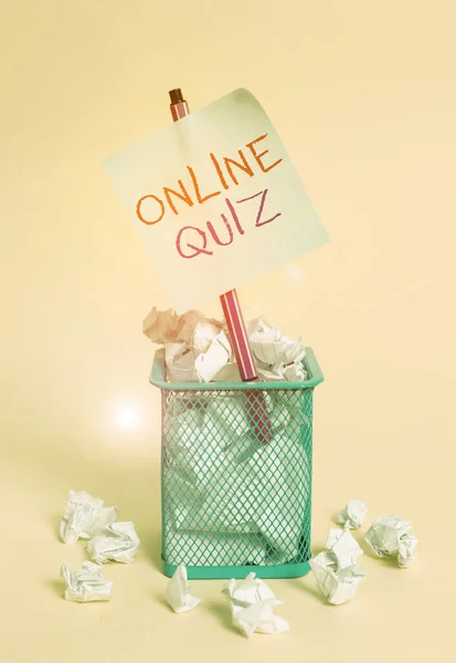 Writing note showing Online Quiz. Business photo showcasing game or a mind sport that are published on the Internet crumpled paper and stationary with paper placed in the trash can.