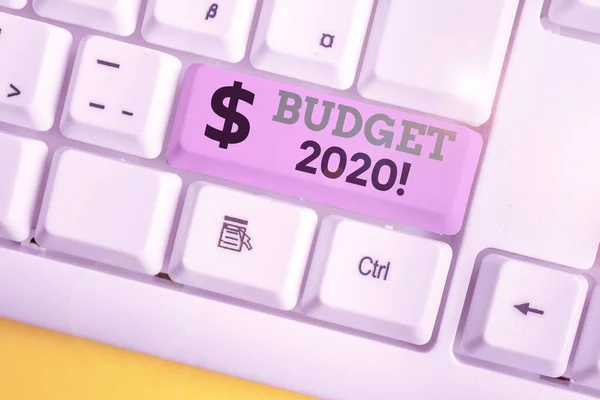Εννοιολογική γραφή χεριού που δείχνει τον προϋπολογισμό 2020. Επαγγελματική φωτογραφία προβολή εκτίμησης των εσόδων και των δαπανών για το επόμενο ή το τρέχον έτος λευκό πληκτρολόγιο PC με χαρτί σημείωσης πάνω από το λευκό φόντο. — Φωτογραφία Αρχείου