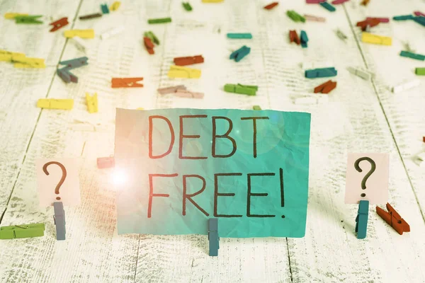 Handwriting text Debt Free. Concept meaning does not owning any money to any individual or companies Scribbled and crumbling sheet with paper clips placed on the wooden table.