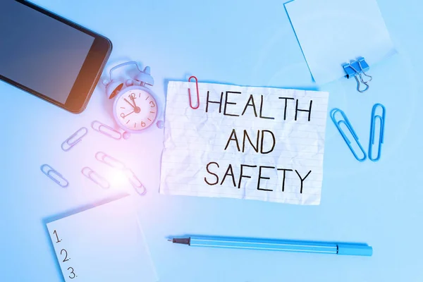 Handwriting text Health And Safety question. Concept meaning regulations and procedures intended to prevent accident Alarm clock clips notepad smartphone rubber band marker colored background.