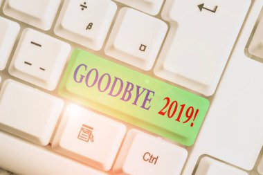 El yazısı. Hoşça kal 2019. Kavram, geçen yılın sonunda ya da ayrılırken iyi dilekleri ifade etmek anlamına gelir beyaz arkaplan anahtar boşluğunun üzerinde boş not kağıdıyla beyaz pc klavye.