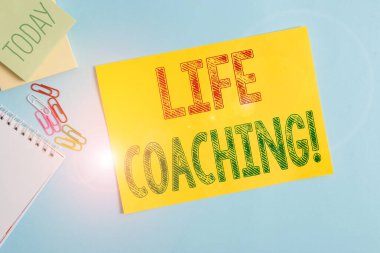 Yaşam koçluğunu gösteren kavramsal el yazısı. Kariyerlerindeki hedeflerine ulaşmak için kullandıkları iş fotoğraflarının sergilenmesi ve Pastel Backdro 'nun üzerine yerleştirilen yazı ekipmanları