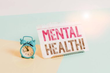 Word writing text Mental Health. Business concept for demonstratings condition regard to their psychological well being Mini size alarm clock beside a Paper sheet placed tilted on pastel backdrop.