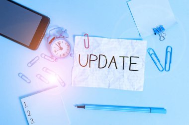 Handwriting text Update. Concept meaning make something more modern or up to date like software programs Alarm clock clips notepad smartphone rubber band marker colored background.