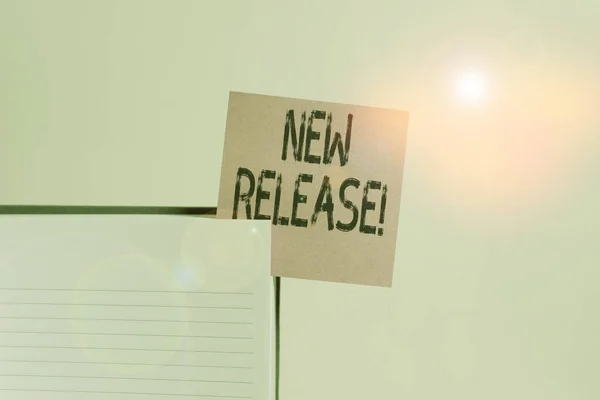 Text sign showing New Release. Conceptual photo announcing something newsworthy recent product Upper view lined hard cover note book sticky note inserted clear background.