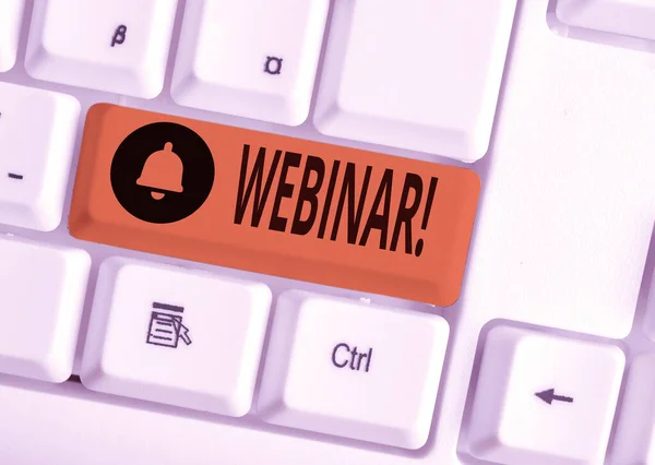 ウェビナーを示すテキスト記号。概念的な写真セミナーやインターネットホワイトPCキーボード上で行われる他のプレゼンテーションの種類は、白い背景キーのコピースペースの上に空のノート紙を持つ. — ストック写真
