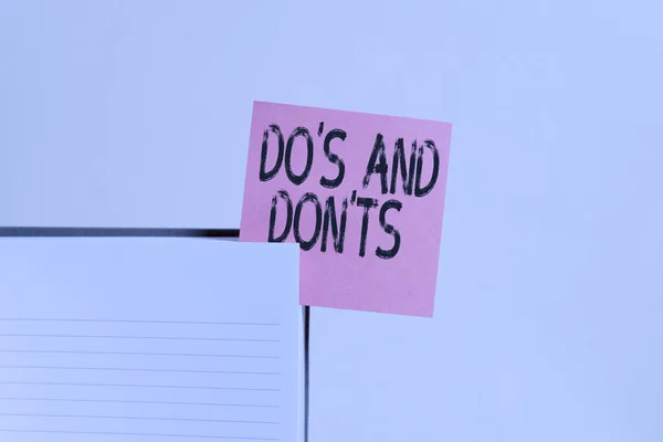 Text sign showing Do S And Don tS. Conceptual photo Rules or customs concerning some activity or actions Upper view lined hard cover note book sticky note inserted clear background.