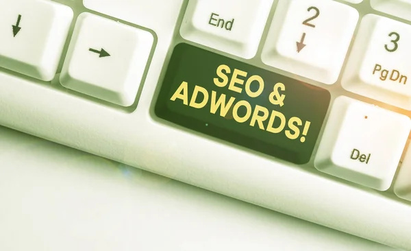 Conceptual hand writing showing Seo And Adwords. Business photo showcasing they are main tools components of Search Engine Marketing White pc keyboard with note paper above the white background. — Stock Photo, Image