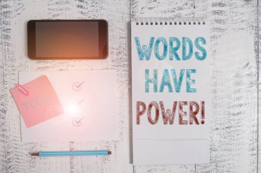 Kelimelerin Gücü Olduğunu gösteren bir not yazıyorum. İş fotoğraflarının sergilenmesi birine zarar verme ya da zarar verme yetenekleri var. Kare şeklindeki not defteri, ahşap arka plandaki telefon yapışkan notları..