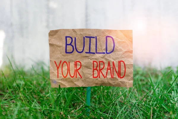 문자를 쓰는 것은 여러분의 브랜드를 만듭니다. 광고 캠페인을 이용하여 브랜드의 평등을 증진시키기 위한 비즈니스 개념은 막대기에 붙어 있는 종이를 으깨고 푸른 초원 지대에 위치시켰다. — 스톡 사진