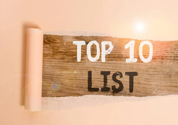 Handwriting text Top 10 List. Concept meaning the ten most important or successful items in a particular list Cardboard which is torn in the middle placed above a wooden classic table.