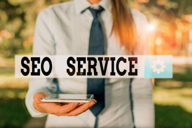 Seo Servisini gösteren kavramsal el yazısı. İnternet sitesinin görünürlüğünü arttırmak için iş fotoğrafı gösterme teknikleri ve prosedürleri tişörtlü iş kadını dizüstü bilgisayarlı ve cep telefonlu.