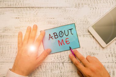 Conceptual hand writing showing About Me. Business photo text telling someone list of your good and bad traits and past events Hand hold note paper near writing equipment and smartphone.