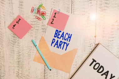 Word writing text Beach Party. Business concept for large group of showing are organizing an event at the beach Envelope sheet paper sticky notes ballpoint notepad clips wooden background.