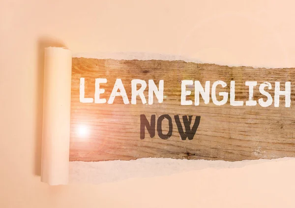 Handwriting text Learn English Now. Concept meaning gain or acquire knowledge and skill of english language Cardboard which is torn in the middle placed above a wooden classic table.