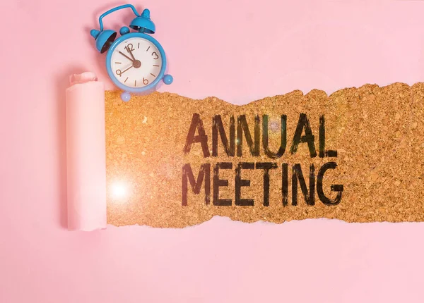 Text sign showing Annual Meeting. Conceptual photo yearly meeting of the general membership of an organization Alarm clock and torn cardboard placed above a wooden classic table backdrop.