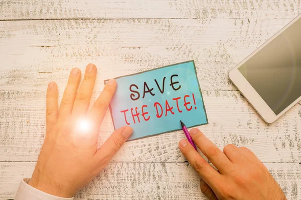 Conceptual hand writing showing Save The Date. Business photo text reserve the mentioned future wedding date on their calendar Hand hold note paper near writing equipment and smartphone. — Stock Photo, Image