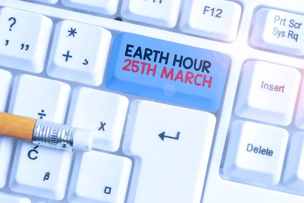 地球時間3月25日を示すメモを書く。惑星へのシンボルコミットメントを示すビジネス写真組織化された世界基金白の背景の上にノートパソコンのキーボード. — ストック写真