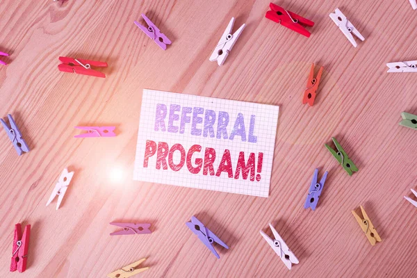 Handwriting text writing Referral Program. Concept meaning employees are rewarded for introducing suitable recruits Colored clothespin papers empty reminder wooden floor background office.