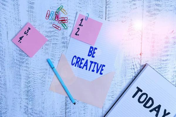 Word writing text Be Creative. Business concept for involving the use of the imagination to create something Envelope sheet paper sticky notes ballpoint notepad clips wooden background.