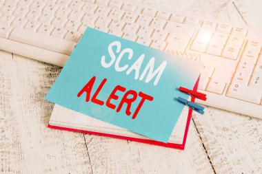 Scam Alert 'i gösteren not yazılıyor. İş fotoğraflarında istenmeyen e-postalar gösteriliyor. Ucuz bir defter hatırlatma broşu ve çivilenmiş ahşap çarşaf..