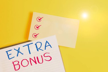 Conceptual hand writing showing Extra Bonus. Business photo text an extra amount of money that is added to someone s is pay Empty orange paper with copy space on the yellow table. clipart