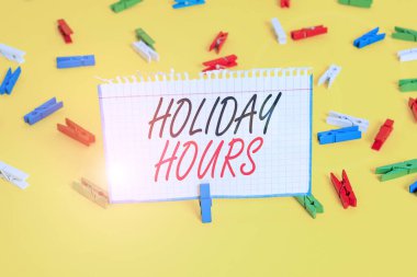 Holiday Hours 'u gösteren bir not yazıyorum. İş fotoğrafçıları her saat için normal ücretlerinin iki katını alıyor. Renkli çamaşır iğnesi kağıtları boş sarı zemin ofisini hatırlatıyor..