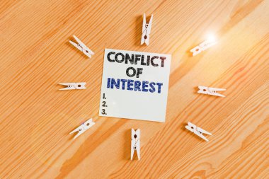 Word writing text Conflict Of Interest. Business concept for disagreeing with someone about goals or targets Colored clothespin papers empty reminder wooden floor background office.