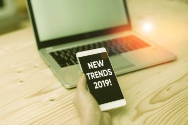Conceptual hand writing showing New Trends 2019. Business photo showcasing general direction in which something is developing woman with laptop smartphone and office supplies technology.