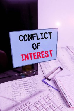 Writing note showing Conflict Of Interest. Business photo showcasing disagreeing with someone about goals or targets Note paper taped to black computer screen near keyboard and stationary.