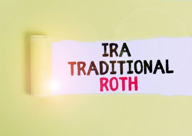 Text sign showing Ira Traditional Roth. Conceptual photo are tax deductible on both state and federal Cardboard which is torn in the middle placed above a plain table backdrop.