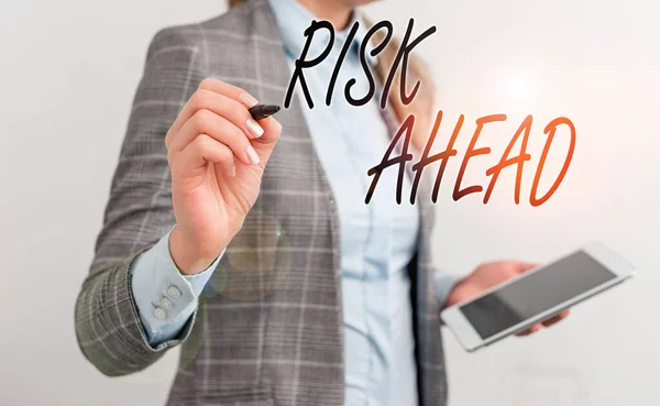 Handwriting text writing Risk Ahead. Concept meaning A probability or threat of damage, injury, liability, loss Business woman pointing in empty space with pen and mobile phone. — Stock Photo, Image