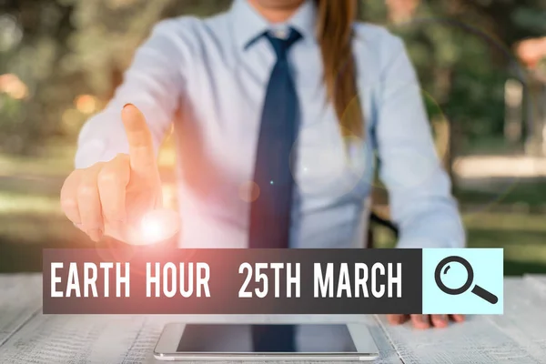 Написання тексту Earth Hour 25 March. Концепція означає зобов'язання символізувати планету Організоване світове фонд Жіночий бізнес, який сидить за столом і тримає мобільний телефон. — стокове фото