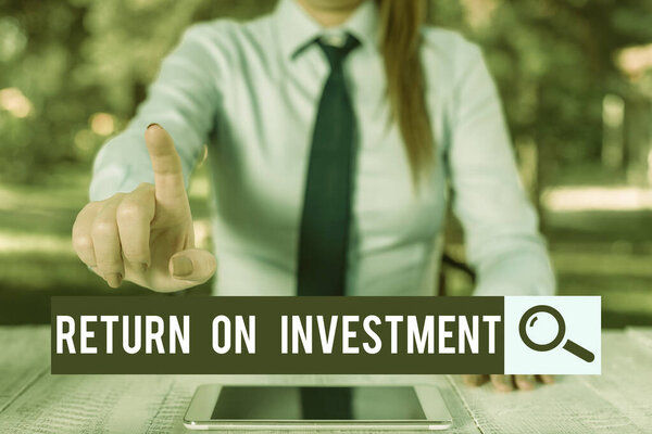 Handwriting text writing Return On Investment. Concept meaning Ratio between the Net Profit and Cost invested Female business person sitting by table and holding mobile phone.