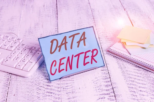 Word writing text Data Center. Business concept for a repository that houses computing facilities like servers Notepaper stand on buffer wire in between computer keyboard and math sheets.