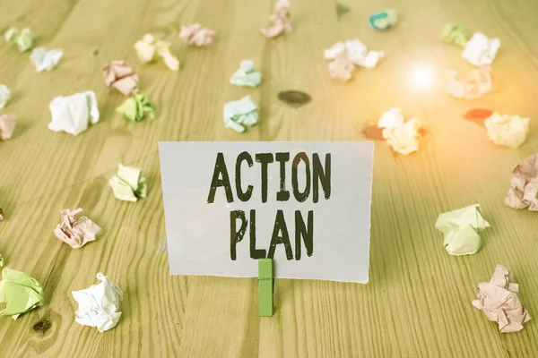 Writing note showing Action Plan. Business photo showcasing detailed plan outlining actions needed to reach goals or vision Colored crumpled papers wooden floor background clothespin.