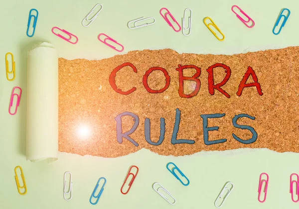 Handwriting text Cobra Rules. Concept meaning continuing group health insurance coverage after a job loss Paper clip and torn cardboard placed above a wooden classic table backdrop. — ストック写真