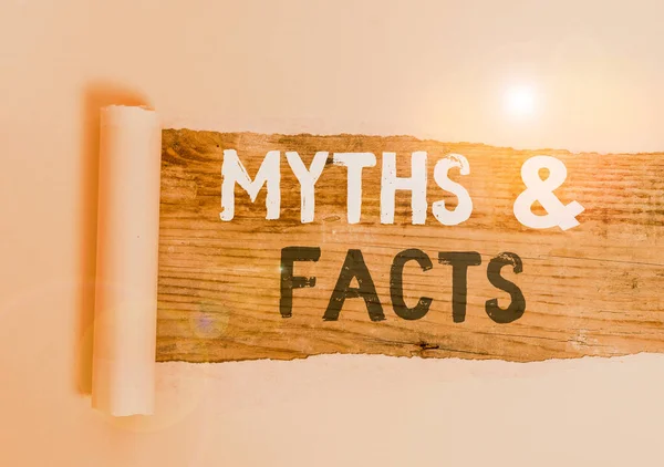 Handwriting text Myths And Facts. Concept meaning usually traditional story of ostensibly historical events Cardboard which is torn in the middle placed above a wooden classic table. — Stock Photo, Image